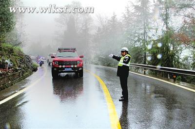 圖為羅旦華冒雨為過往車輛導(dǎo)航。